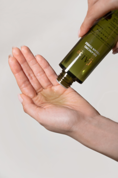 Ręka wylewa łagodny, wegański tonik d'Alba Balancing Vegan Toner z zielonej butelki do otwartej dłoni.