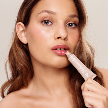 Kobieta aplikuje peptydowy balsam do ust Say Hi Glassy Lips Candy, wegański, nawilżający z efektem glow.