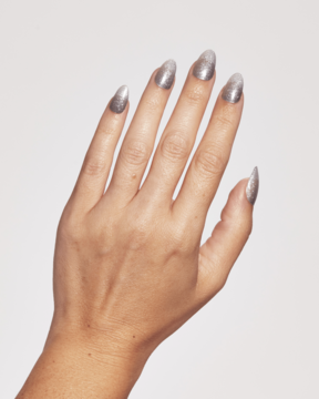 Widok z góry dłoni z długimi, szpiczastymi paznokciami, pokrytymi metalicznymi srebrnymi naklejkami Ardell.