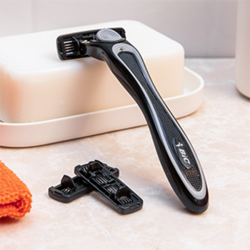 Maszynka BIC Hybrid Flex 4 z 4 ostrzami, czarno-szara rączka, stoi obok dwóch wkładów na jasnym blacie.