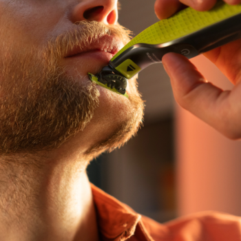 Mężczyzna przycina zarost na brodzie maszynką Philips OneBlade z zielonym ostrzem 360, zbliżenie na twarz.