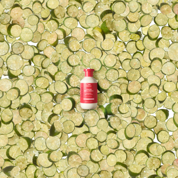 Różowy szampon Wella Professionals Invigo Color Brilliance, na tle z licznych, ułożonych plasterków limonek.