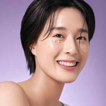 Uśmiechnięta kobieta, krople PURITO Timeless Bloom Retinol Spot Cream pod okiem, dla gładkiej cery bez zmarszczek.