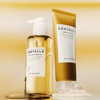 Skin1004 Madagascar Centella Duo: złoty olejek w butelce z pompką i kremowa pianka w tubce, stojące na złotym tle.