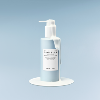 Łagodne mleczko SKIN1004 Hyalu-Cica w błękitnej butelce z pompką, z wyciekającym białym płynem.