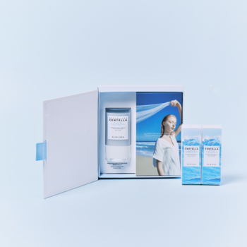 Hyalu-Cica Sunsational Kit. Otwarte białe pudełko z serum i plażową grafiką, obok dwa serum i sztyft SPF, widok z góry.