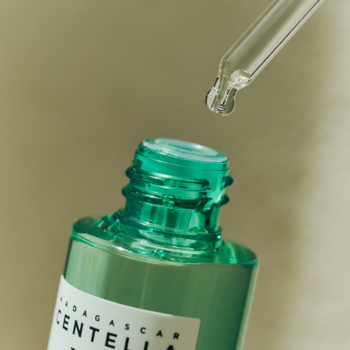 Madagascar Centella Tea-Trica SOS serum w zielonej butelce, kropla płynu z pipety opada, zbliżenie.