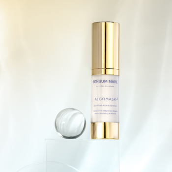 Sensum Mare Algomask, kremowa maska pod oczy w złotej butelce z jasnym korpusem, obok lśniąca szklana kula.