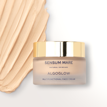 Sensum Mare Algoglow krem rozświetlający w matowym słoiczku ze złotą nakrętką, na beżowej smudze kremu.