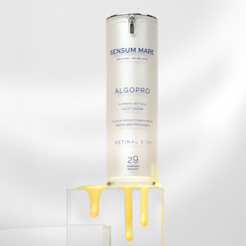 Biała butelka Sensum Mare ALGOPRO serum z retinalem 0,16%, widok z przodu, złote krople spływają po postumencie.