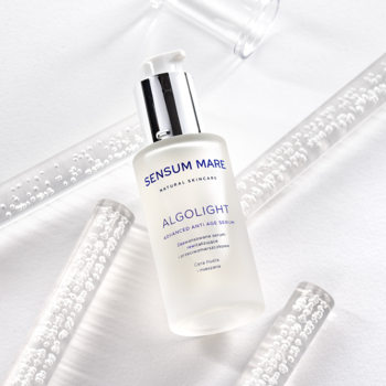 Sensum Mare Algolight serum do twarzy w butelce z matowego szkła, widok z góry na tle przezroczystych tub.