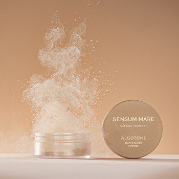 Sensum Mare Algotone matujący puder sypki, otwarty słoiczek z chmurą proszku, obok zamknięty kompakt na beżowym tle.