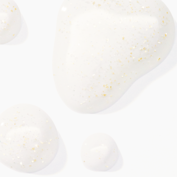 Trzy błyszczące krople olejku Catrice Glam In Gold ze złotymi drobinkami na białym tle, widok z góry.