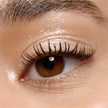 Zbliżenie na brązowe oko, z długimi, czarnymi rzęsami pokrytymi tuszem, dewy skóra powiek, efekt glow.