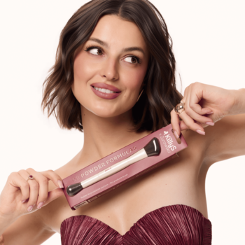 Kobieta prezentuje dwustronny pędzel KillyS x Żurawska do pudru i rozświetlacza w różowym opakowaniu.