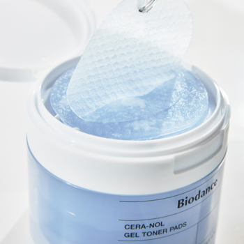 Biodance CERA-NOL GEL TONER PADS, niebieskie żelowe płatki w otwartym białym słoiku, z uniesionym jednym płatkiem.