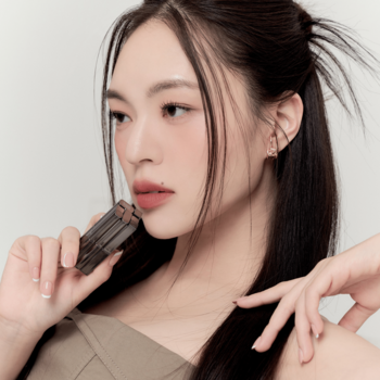 Kobieta z matowymi ustami trzyma pomadkę Muzigae Mansion Prime; widoczne aksamitne wykończenie ust.