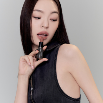 Kobieta prezentuje matową pomadkę Muzigae Mansion Maxi w odcieniu nude z efektem soft blur na jasnym tle.