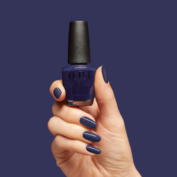 OPI Havin' a Candy Ol' Time, ciemnoniebieski lakier do paznokci. Dłoń trzyma butelkę, paznokcie pomalowane tym odcieniem.