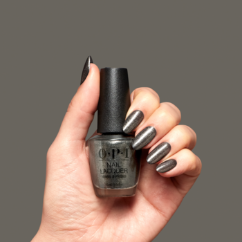 Dłoń trzyma lakier OPI Tempted to Lick-orice, metaliczna czerń. Paznokcie pomalowane tym wyrazistym odcieniem.