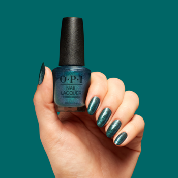 Dłoń trzyma butelkę lakieru OPI Yuletide Sweetings w głębokiej zieleni z niebieskim połyskiem. Paznokcie pomalowane tym samym odcieniem.