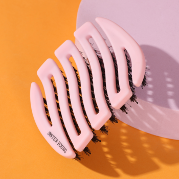 Różowa szczotka MILA Pocket Sister Young, z napisem SISTER YOUNG, widok z góry na dwukolorowym tle.