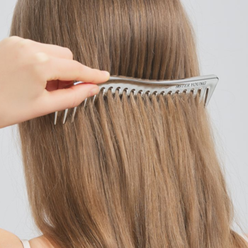 Grzebień ZURI Sister Young z szerokimi zębami, antystatyczny, rozczesuje długie, brązowe włosy ręką.