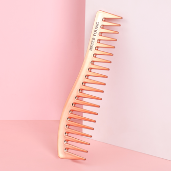 Rose Gold antystatyczny grzebień ZURI Sister Young z szerokimi zębami, oparty o pastelowe różowe tło.