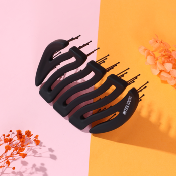 Czarna kompaktowa szczotka MILA Pocket Sister Young o falistej konstrukcji z nylonowymi szpilkami, na różowo-pomarańczowym tle.