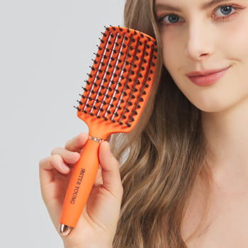 Pomarańczowa wentylowana szczotka Ovia Sister Young z włosiem dzika, trzymana przez kobietę do rozczesywania włosów.