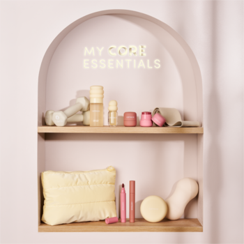 Regal z neonem "MY CORE ESSENTIALS", na pastelowych półkach hantle, butelki i akcesoria do pielęgnacji i jogi.
