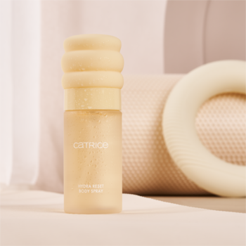 Catrice Hydra Boost Body Spray, beżowa butelka z matowym szkłem i karbowaną nakrętką, na jasnym, miękkim tle.