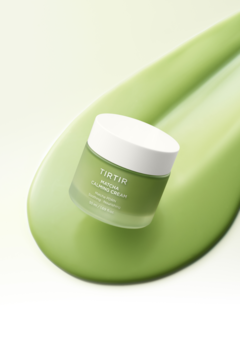 TIRTIR Matcha Calming Cream w małym, zielonym słoiku z białą pokrywką, widoczne logo, na kremowej smudze.