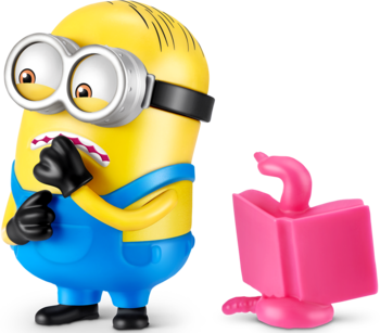 Żółta figurka Minionka Gumi Yum Surprise z przodu, wystraszony, obok różowy spust dynamitu.