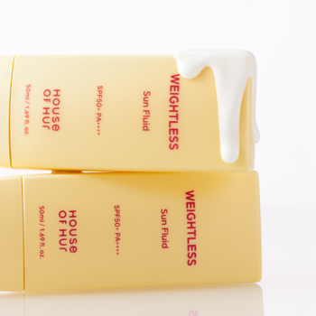 HOUSE OF HUF WEIGHTLESS Sun Fluid SPF50+, dwie żółte butelki na białym tle, z górnej spływa biały płyn.