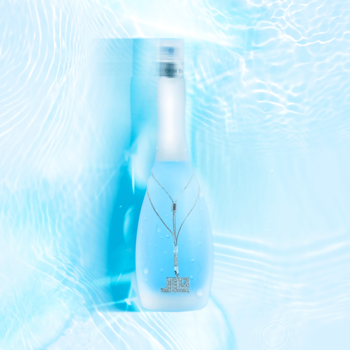 Glow by JLo Pure, elegancki flakon perfum w błękitnej wodzie z falami, symbolizujący świeżość i czystość.