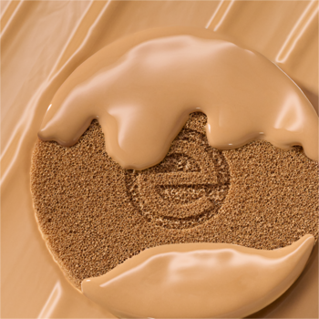 Podkład essence silky CUSHION, średni odcień beżu, spływa po brązowej gąbce z wytłoczonym logo.