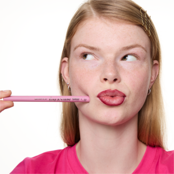 Kobieta z różową konturówką essence line & STAIN! TATTOO LIP LINER 01 obok ust, robi zabawny wyraz twarzy.