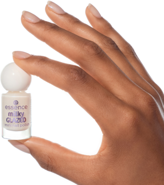 Ręka trzyma mini lakier essence milky GLAZED 21. Mleczny, transparentny lakier w butelce z białą nakrętką. Ujęcie z bliska.