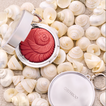 Catrice SEASHELL STORIES C02 Peach Perfect, otwarty kremowy róż w muszlę, na tle piasku i białych muszelek.