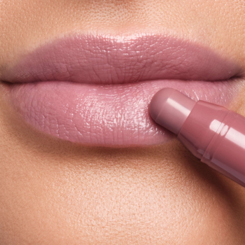 Artdeco Glossy Lip Chubby Celebrity, różowy błyszczyk w sztyfcie na ustach, widok z bliska podczas aplikacji.