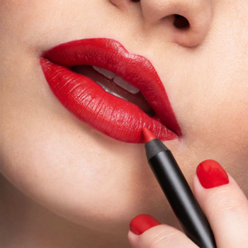 Usta kobiety z czerwoną konturówką Artdeco Soft Lip Liner Fireball podczas aplikacji, dłoń z czerwonym paznokciem.