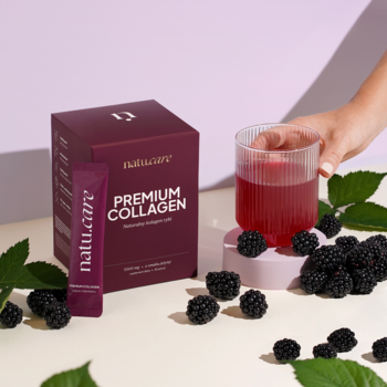 Natu.Care Premium Collagen: purpurowe pudełko i saszetka, szklanka z jeżynowym napojem, świeże jeżyny na jasnym tle.