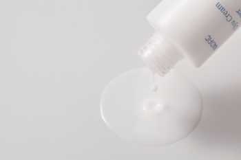 Nacific Uyu Cream Toner, biała tubka wyciska kremowy tonik na gładką, białą powierzchnię, zbliżenie.
