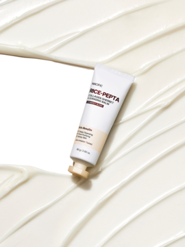 Biała tubka Nacific Rice+Pepta Collagen Sherbet Cleansing Balm, pod kątem, na białym tle z kremowymi falami.