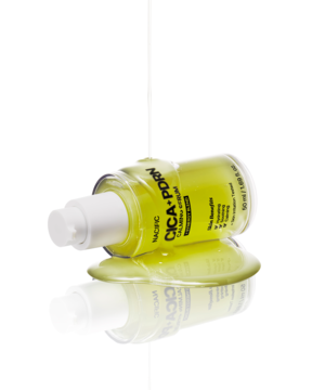 Kojące serum do twarzy Nacific CICA+PDRN Calming w zielonej butelce, leżącej z rozlanym płynem na białym tle.