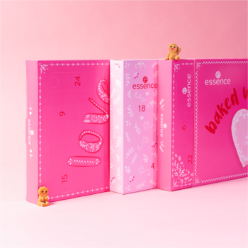 Trzy różowe kalendarze adwentowe essence "baked with love", z napisami i grafikami, stojące pod kątem.