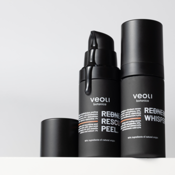Dwie matowe butelki Veoli: REDNESS RESCUE PEEL z pompką i kroplą czarnego peelingu, obok REDNESS WHISPER.