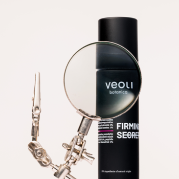 Veoli Botanica FIRMING SECRET, maska ujędrniająca w czarnej butelce, oglądana przez lupę na statywie.