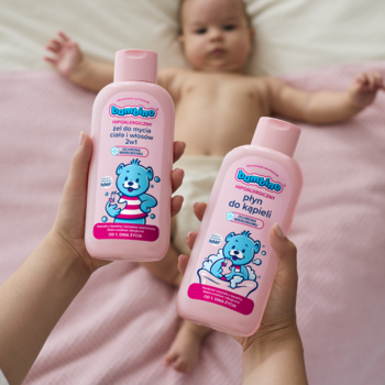 Dłonie trzymają różowe butelki Bambino Żel 2w1 i Płyn do kąpieli dla niemowląt, dziecko leży w tle.